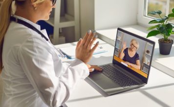 Telemedicine and e-health services. Closeup of doctor waving hand at computer screen greeting senior woman at online consultation. General practitioner using laptop to video call mature patient