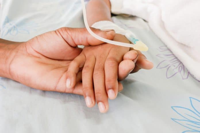 poor man hand holding child's hand,who fever patients have IV tube.